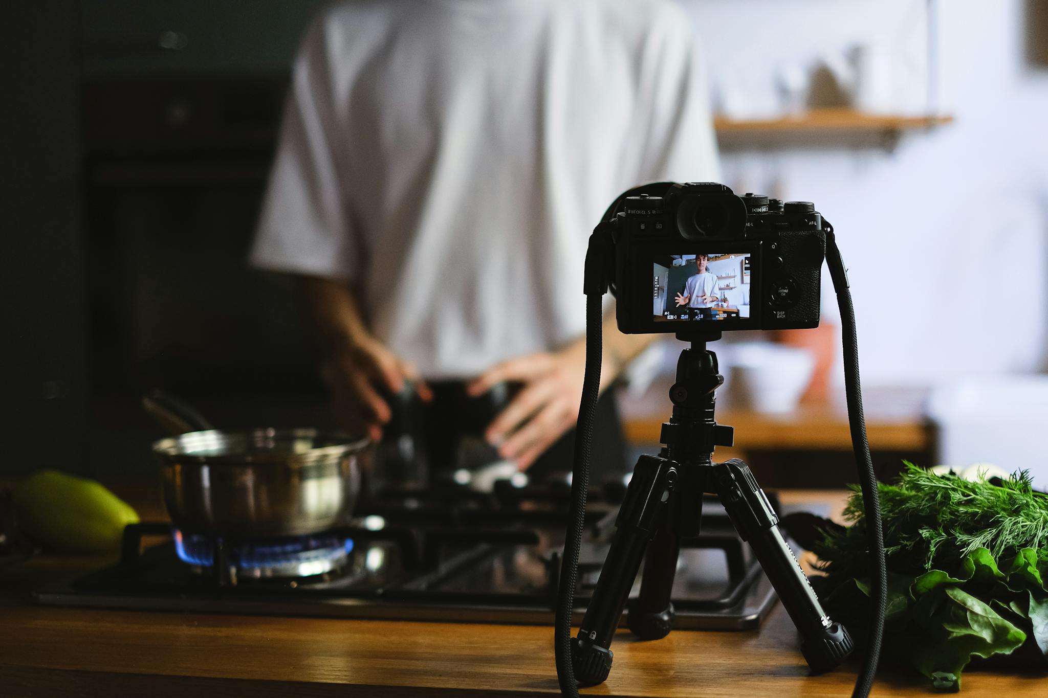 A camera records a cooking tutorial in a modern kitchen with fresh ingredients.