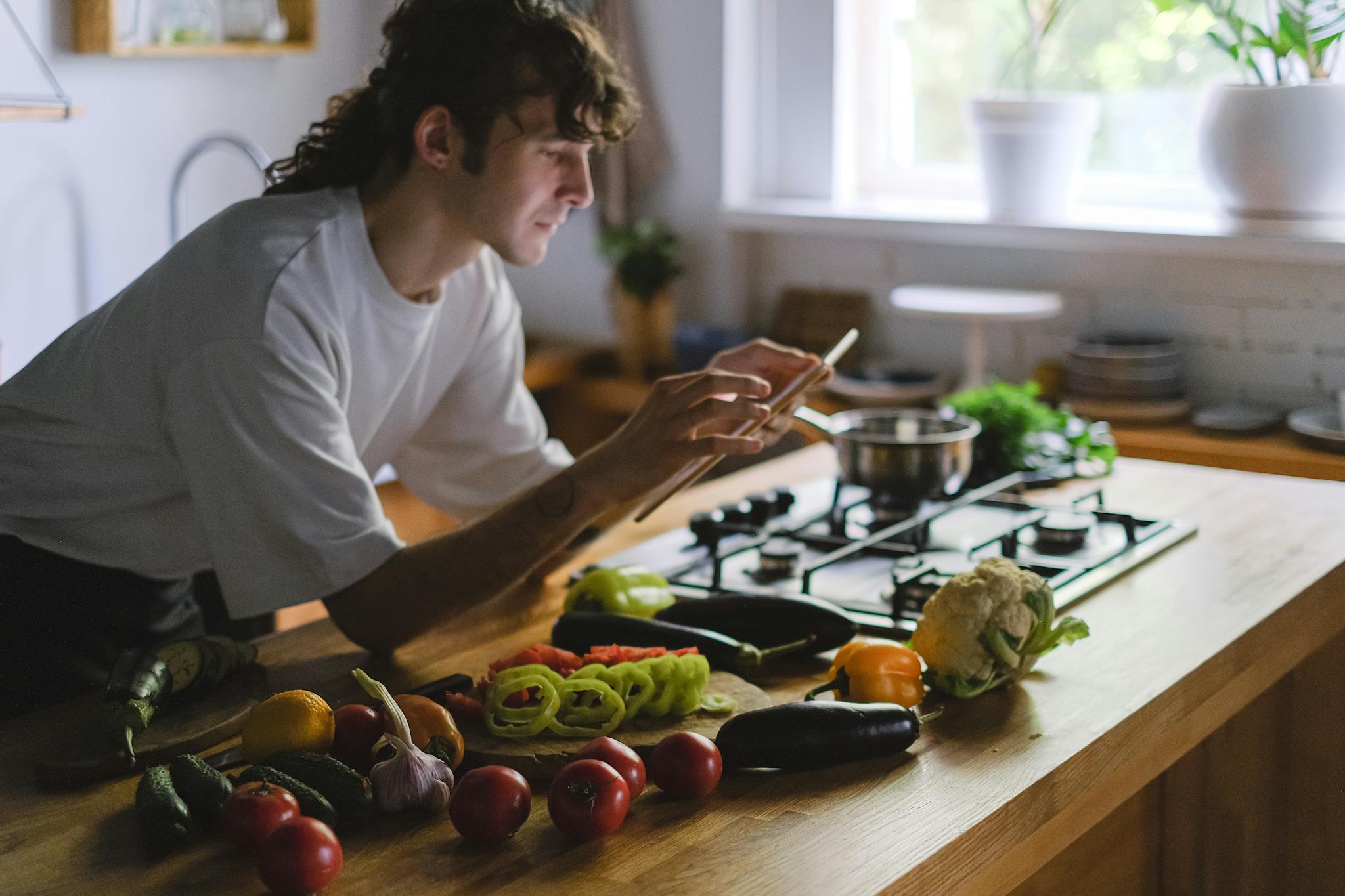 A young chef captures fresh vegetables on a kitchen counter for a blog post.