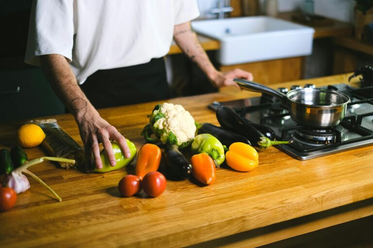Close-up of a chef arranging fresh vegetables on a wooden kitchen counter for a healthy meal.